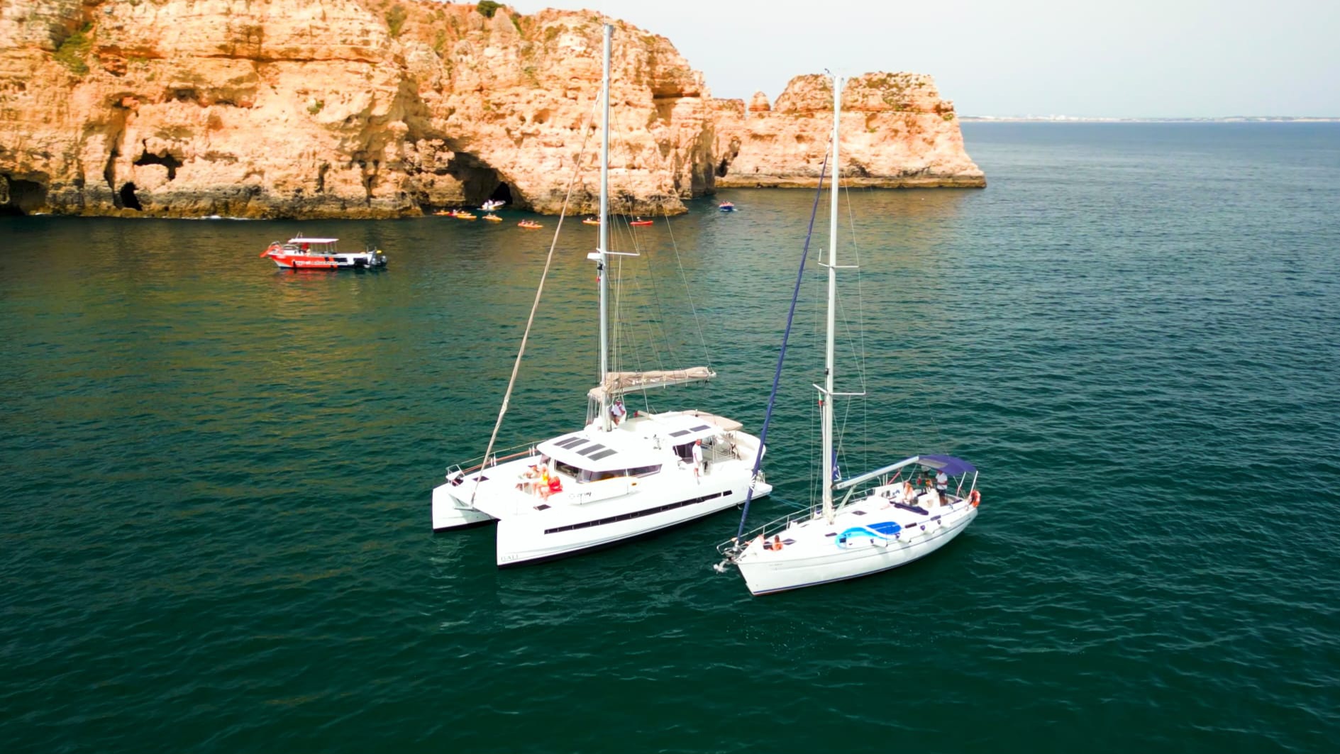 Catamaran e veleiro fundeados junto às falésias douradas da Ponta da Piedade, em Lagos